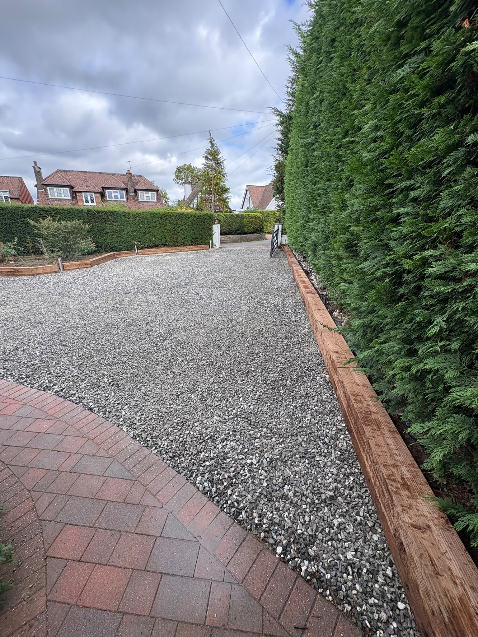 Gravel driveway with timber sleeper edging and block paved path